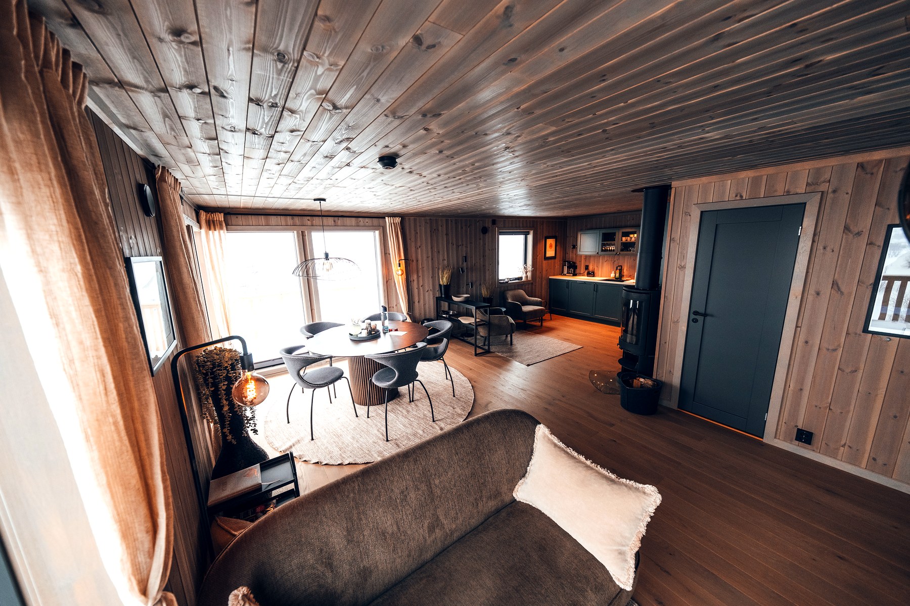 Stue i kveldsstemning med peis og store vinduer