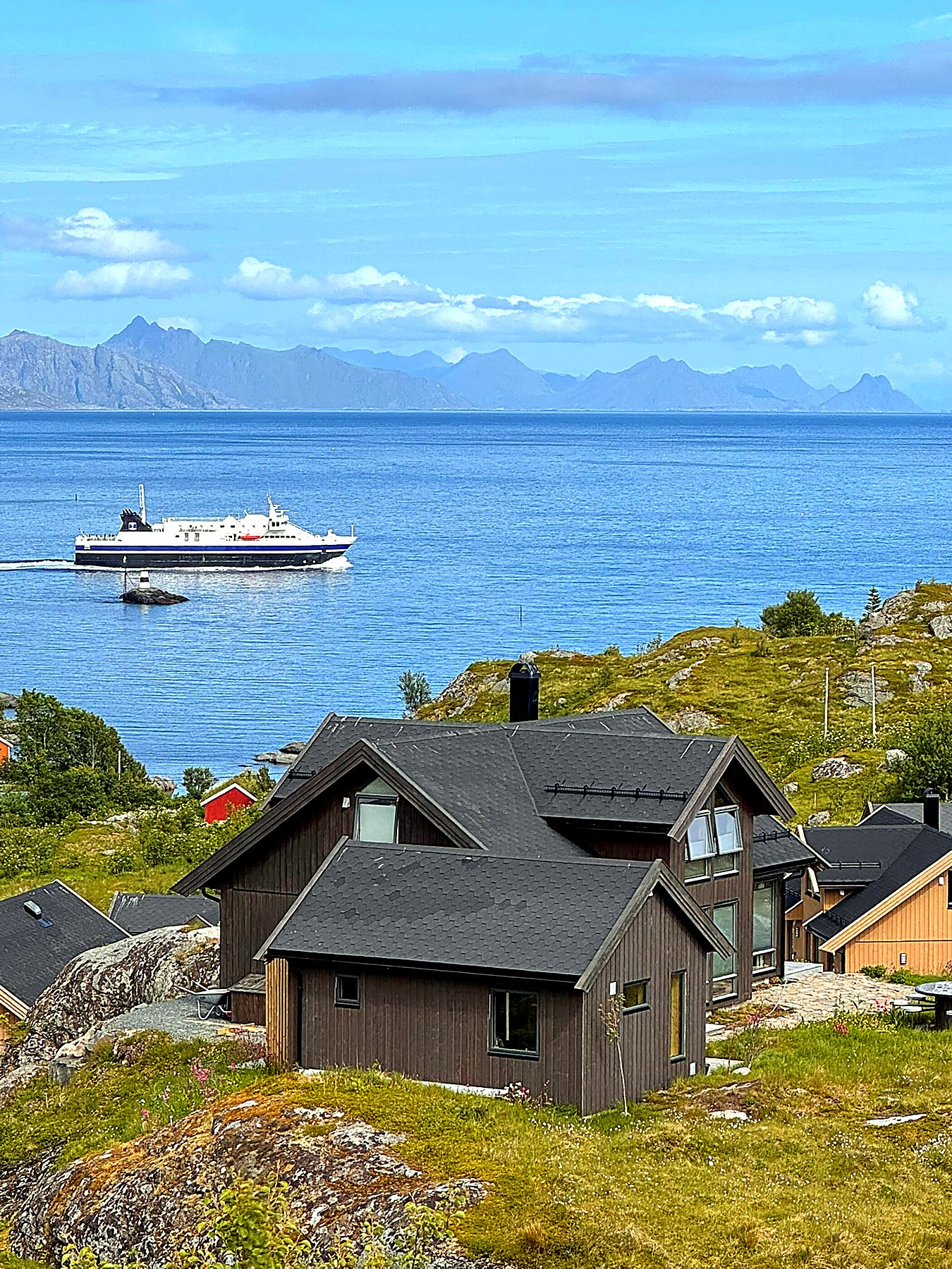 Grønt sommerlandskap og hav ved hytta