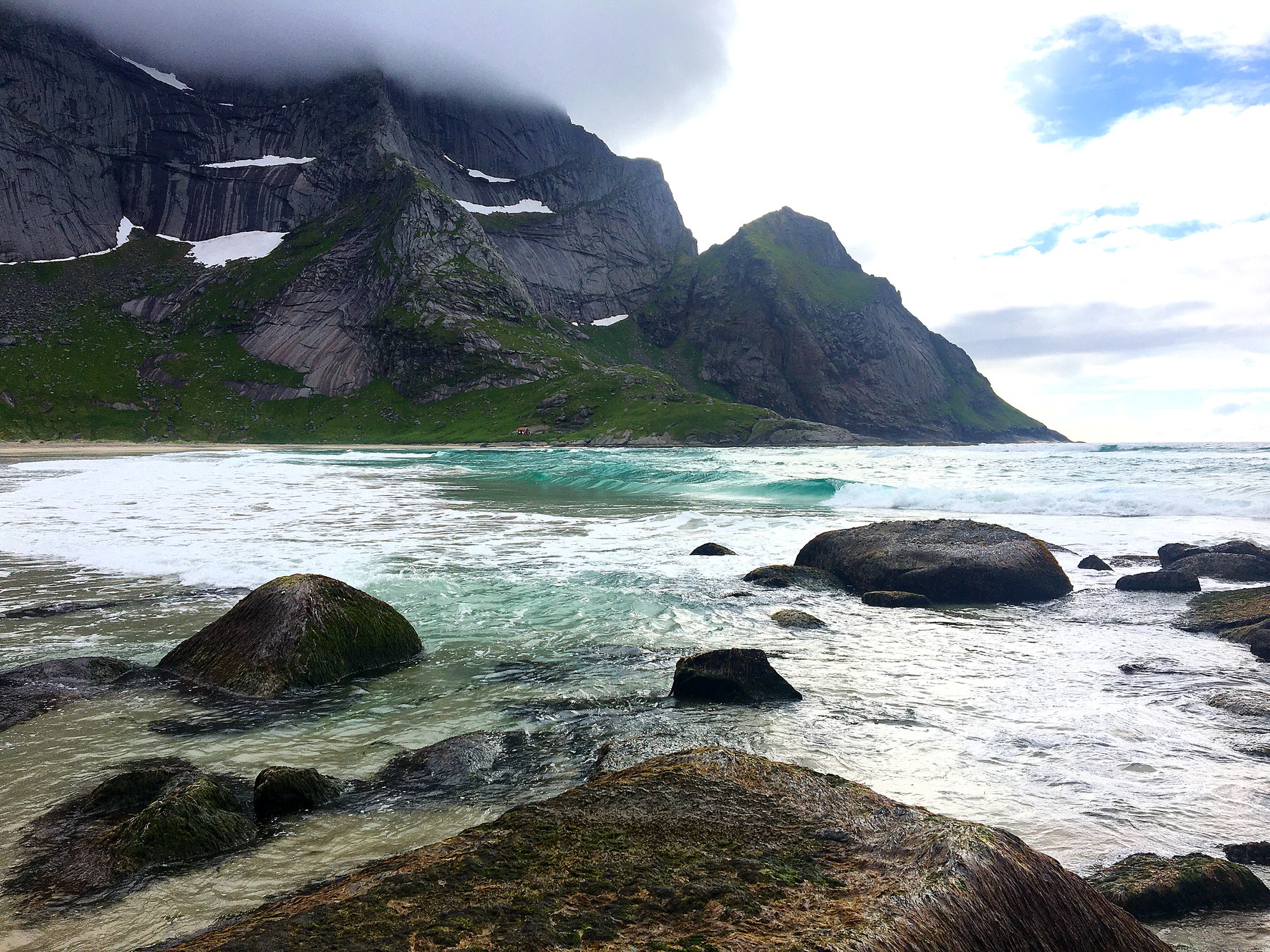 Bunesstranda sett fra fjæra, med bølger og tåkete fjell