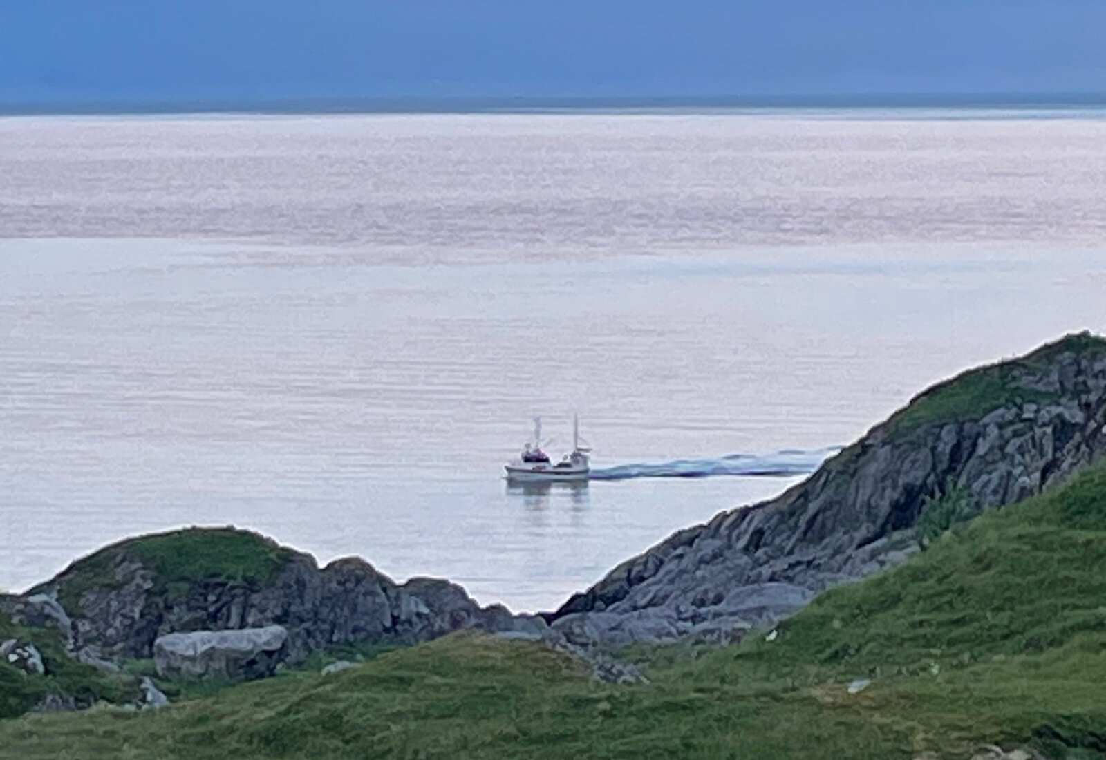 Fiskebåt på blikkstille hav i kveldslys