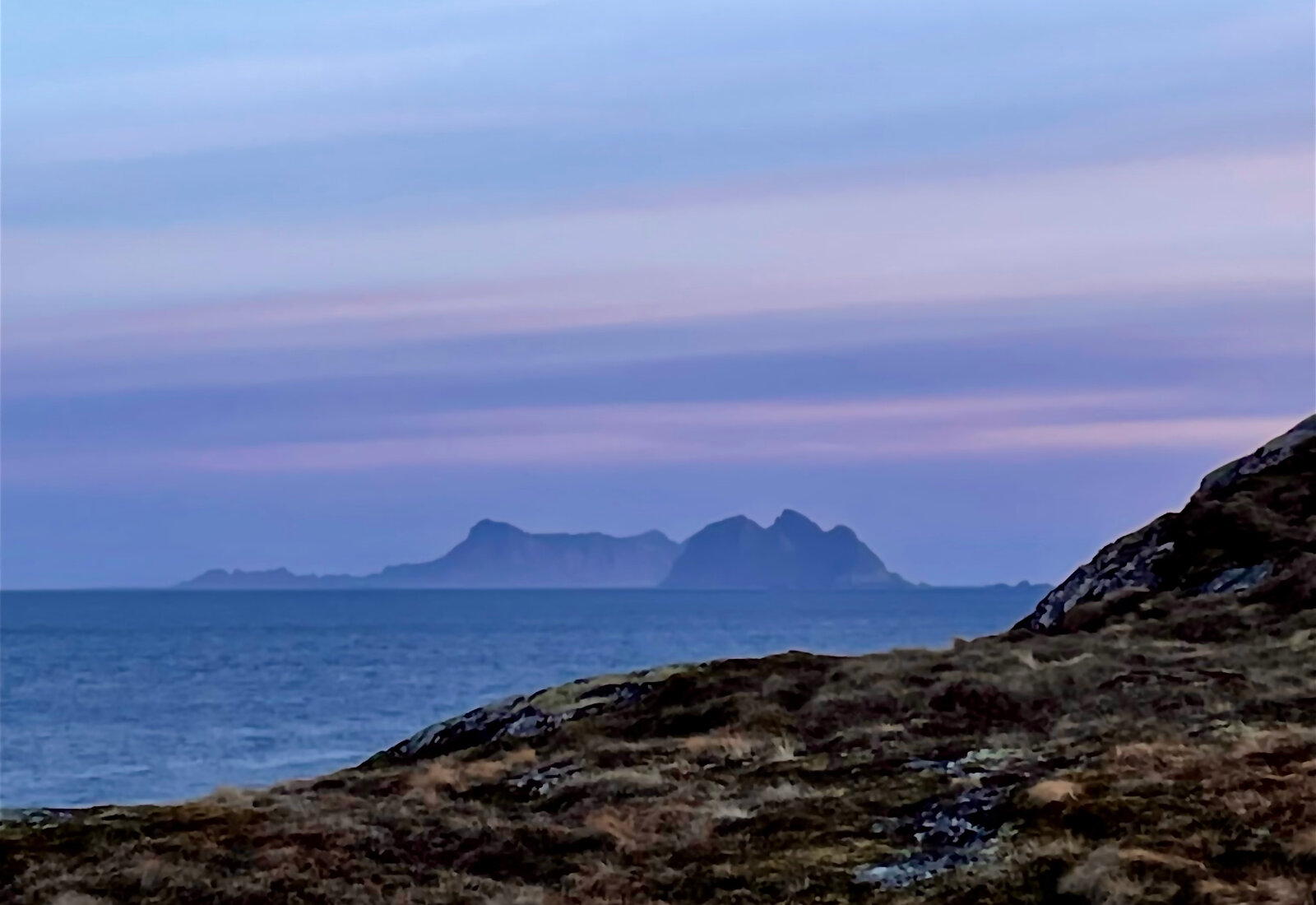 Fargerik kveldshimmel over havet og fjellene i horisonten