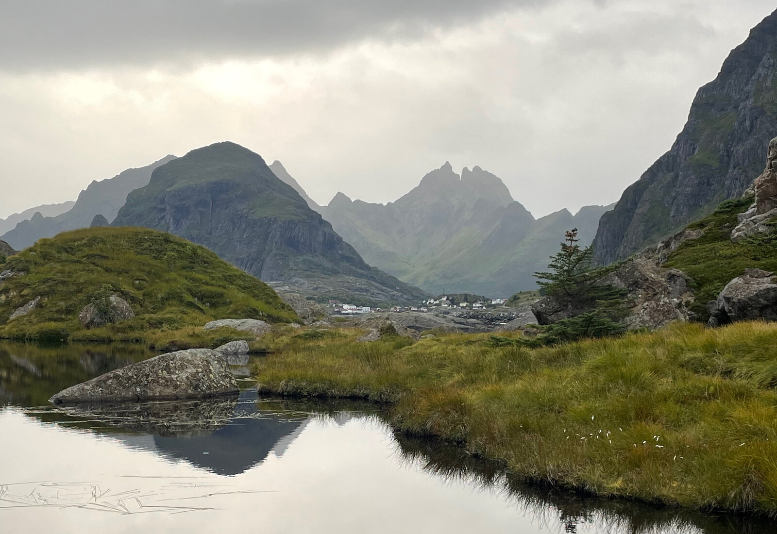 Stille tjern med fjell speilet i vannet