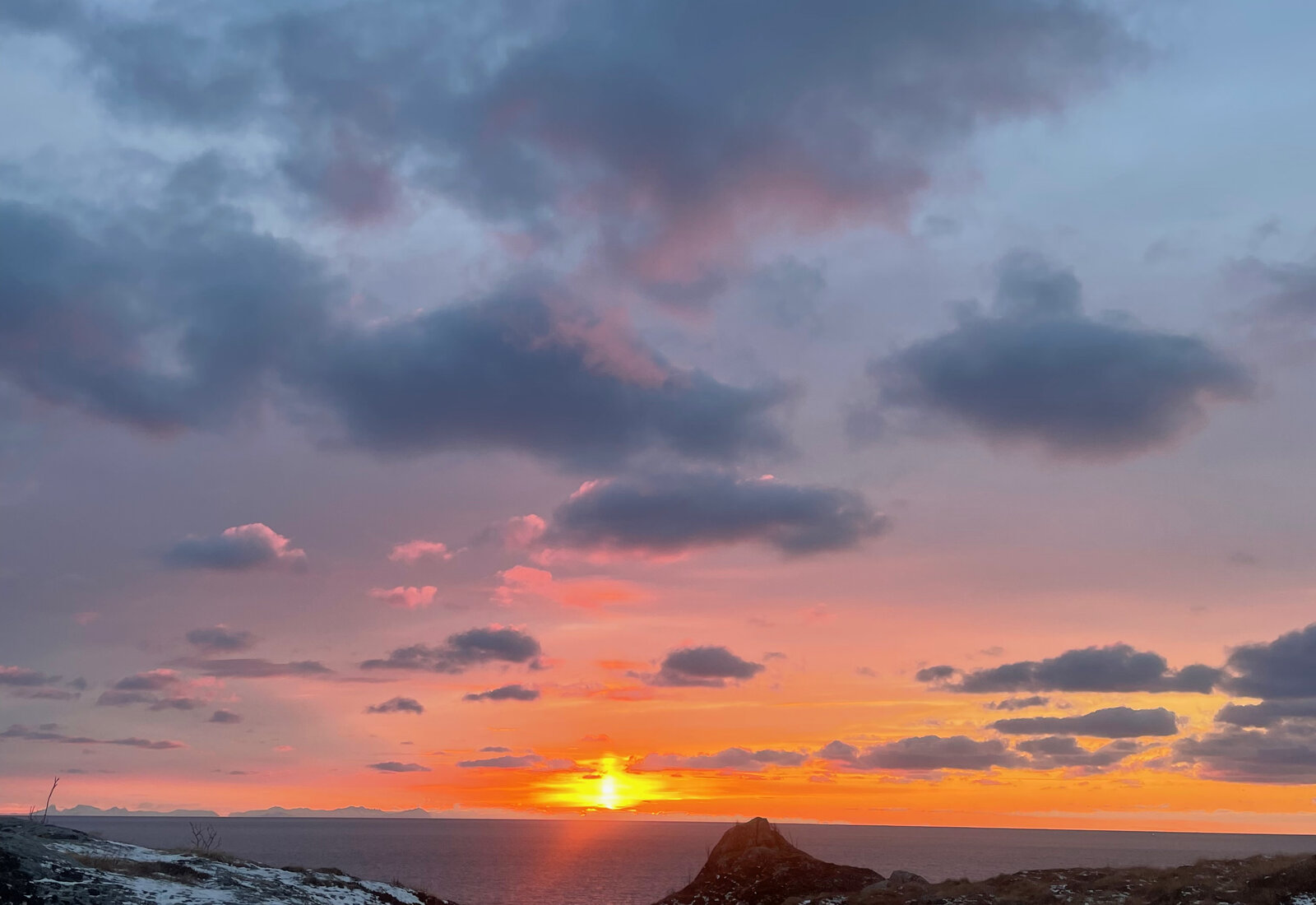 Fargerik vintersoloppgang over havet med snø i forgrunnen